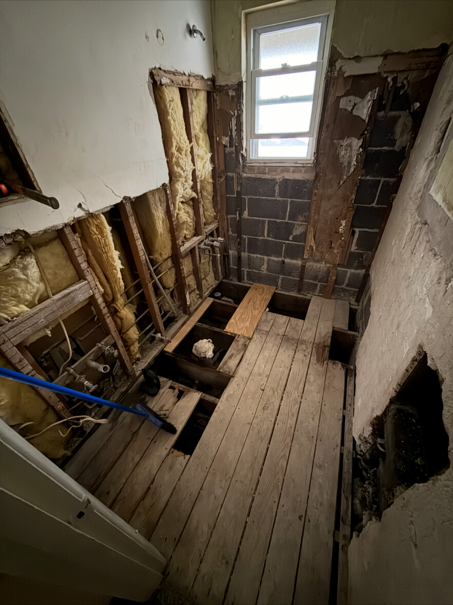 Bathroom stripped to the studs and subfloor with old plumbing exposed during remodel